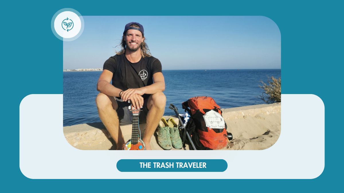 Mann am Strand mit "The Trash Traveler"-Logo auf Rucksack und T-Shirt, Gitarre in der Hand.