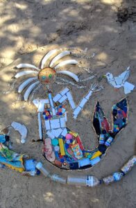 Meerjungfrau-Mosaik aus Plastikmüll und Flaschen im Sand, das die Schönheit der Meereswesen in Kontrast zur Verschmutzung setzt.