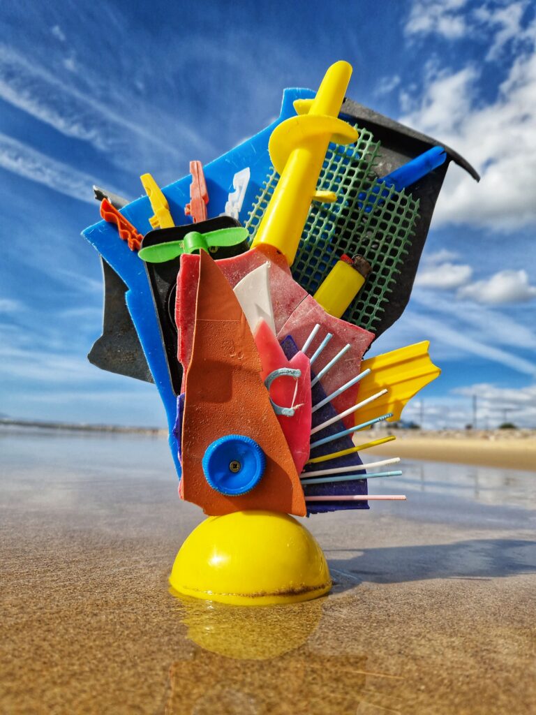 Trophäe der Trash Art Awards, gefertigt aus buntem, gesammeltem Meeresplastik am Strand, symbolisiert die Kreislaufwirtschaft und Wiederverwendung.