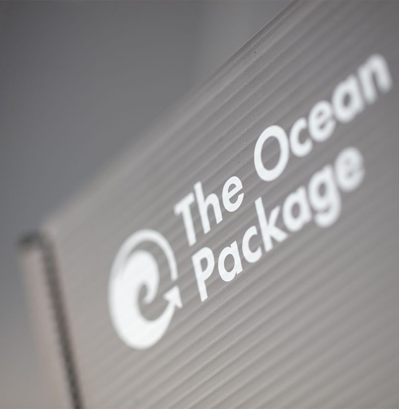 Nahaufnahme einer Mehrweg Versandbox von Ocean Package. Im Fokus steht der Aufdruck des Logos “The Ocean Package”